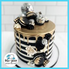 a black and white striped cake with gold trimmings, decorated with chocolate candies