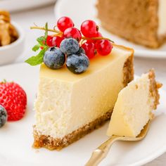 a slice of cheesecake with berries and walnuts on the side next to it