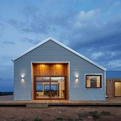 a modern house with an open floor plan in the desert at dusk, lit up by bright lights