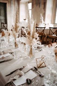 the table is set with clear vases and silverware for an elegant wedding reception