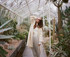 a woman standing in a greenhouse with her hands on her head and looking up at the sky