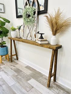 a wooden table topped with vases next to a mirror and potted plant on top of it