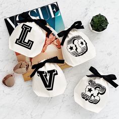 three bags with logos on them sitting next to sunglasses and a magazine, which is laying on a marble surface