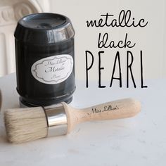 there is a brush next to a jar of black pearl paint on a table with the words metallic black pearl written across it