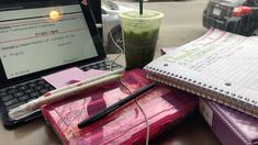 a laptop computer sitting on top of a desk next to a cup of coffee and notebook