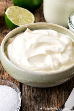 a bowl filled with whipped cream next to some limes