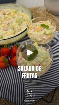 two bowls filled with food sitting on top of a table next to some strawberries