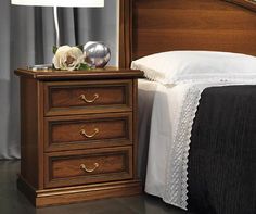 a bed with a wooden headboard and night stand on top of it next to a lamp