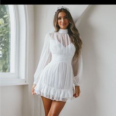 a woman in a white dress posing by a window