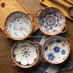 four blue and white dishes sitting on top of a wooden table next to utensils