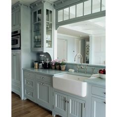 a kitchen with gray cabinets and white counter tops is pictured in this image, the sink has two faucets on it