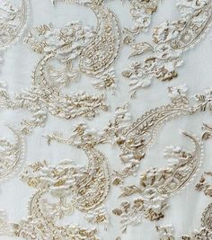 white and gold brocaded fabric with large, intricate designs on it's edges