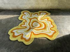 a yellow and white rug sitting on top of a cement floor next to a wall