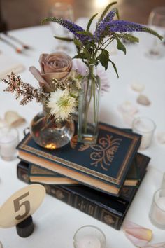 a table topped with books and vases filled with flowers on top of each other