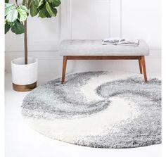 a white and grey rug with a wooden bench in the corner next to a potted plant