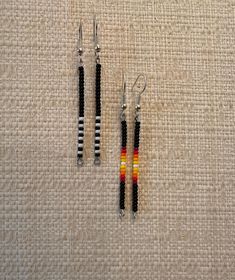 three pairs of beaded earrings sitting on top of a cloth