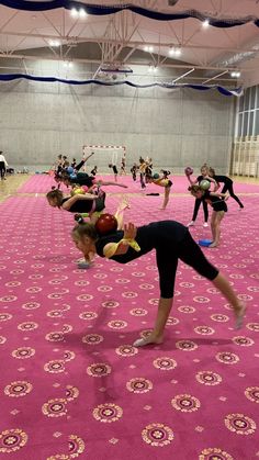 some people are doing yoga in an indoor gym with pink carpet and blue ceilinging