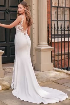 a woman in a white wedding dress standing outside