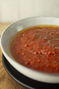 a white bowl filled with sauce on top of a wooden table