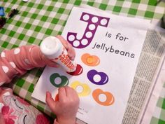 a young child is playing with toys on the table next to a letter j coloring book