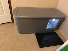 a large gray box sitting on top of a floor next to a door and mat