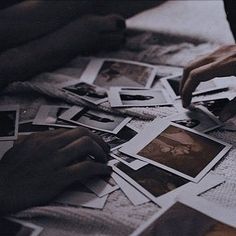 a person sitting at a table surrounded by photos and papers with their hands on them