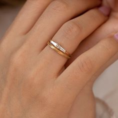 a woman's hand with a gold and white ring on her left hand, wearing a wedding band