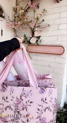 a person holding a pink shopping bag with flowers on it