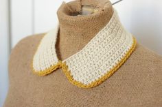 a crocheted collar on a mannequin's neck, with yellow trim