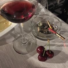 a glass of wine and some cherries on a table