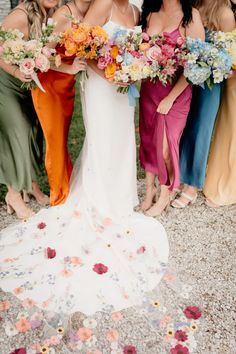 a group of women standing next to each other in dresses and holding bouquets on the ground