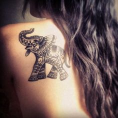 an elephant tattoo on the back of a woman's shoulder