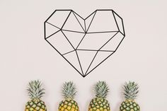 three pineapples are lined up in front of a heart - shaped wall decoration