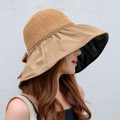 a woman wearing a tan hat with a black brimmed sunhat on her head