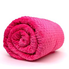 a bright pink blanket folded on top of a white surface with the end rolled up