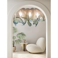 a white chair sitting under a chandelier next to a potted palm tree