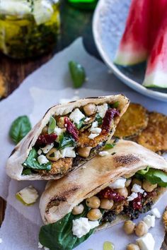 two pita breads filled with vegetables and chickpeas on top of paper