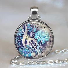 a necklace with music notes and blue flowers on it, sitting on a white surface