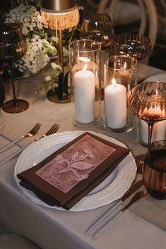 the table is set with candles, plates and napkins for an elegant dinner party