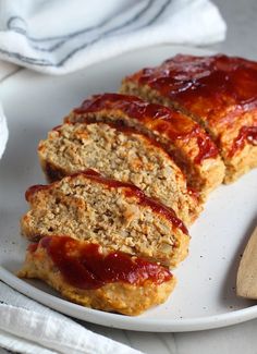 slices of meatloaf on a white plate next to a wooden spoon