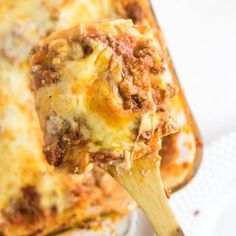 a wooden spoon full of lasagna casserole with meat and cheese on it