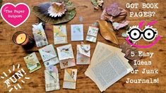 a wooden table topped with lots of books and paper crafts next to a lit candle