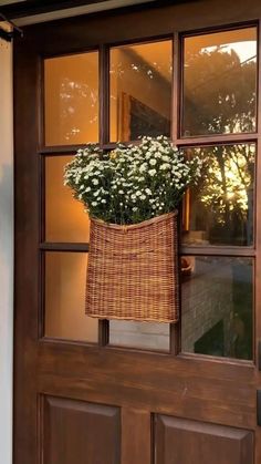 a basket with flowers hanging from the side of a door