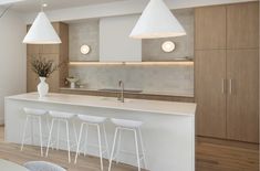 a modern kitchen with white counter tops and bar stools