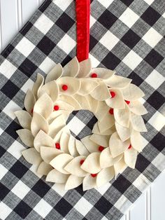 a christmas wreath made out of fabric on a checkered table cloth with a red ribbon