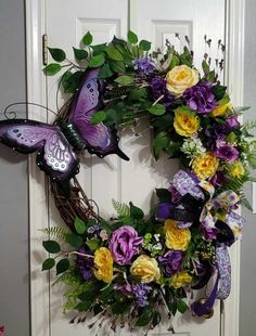 a purple and yellow wreath with butterflies on the front door is adorned with greenery