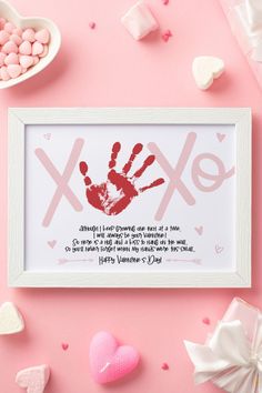 a frame with a handprint on it next to hearts and marshmallows