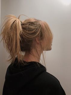 a woman with her hair in a messy ponytail is looking off to the side while wearing a black sweatshirt