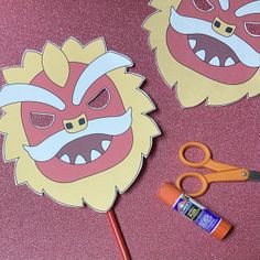 two paper masks with scissors and glue next to them