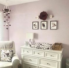 a baby's room with purple walls and white furniture